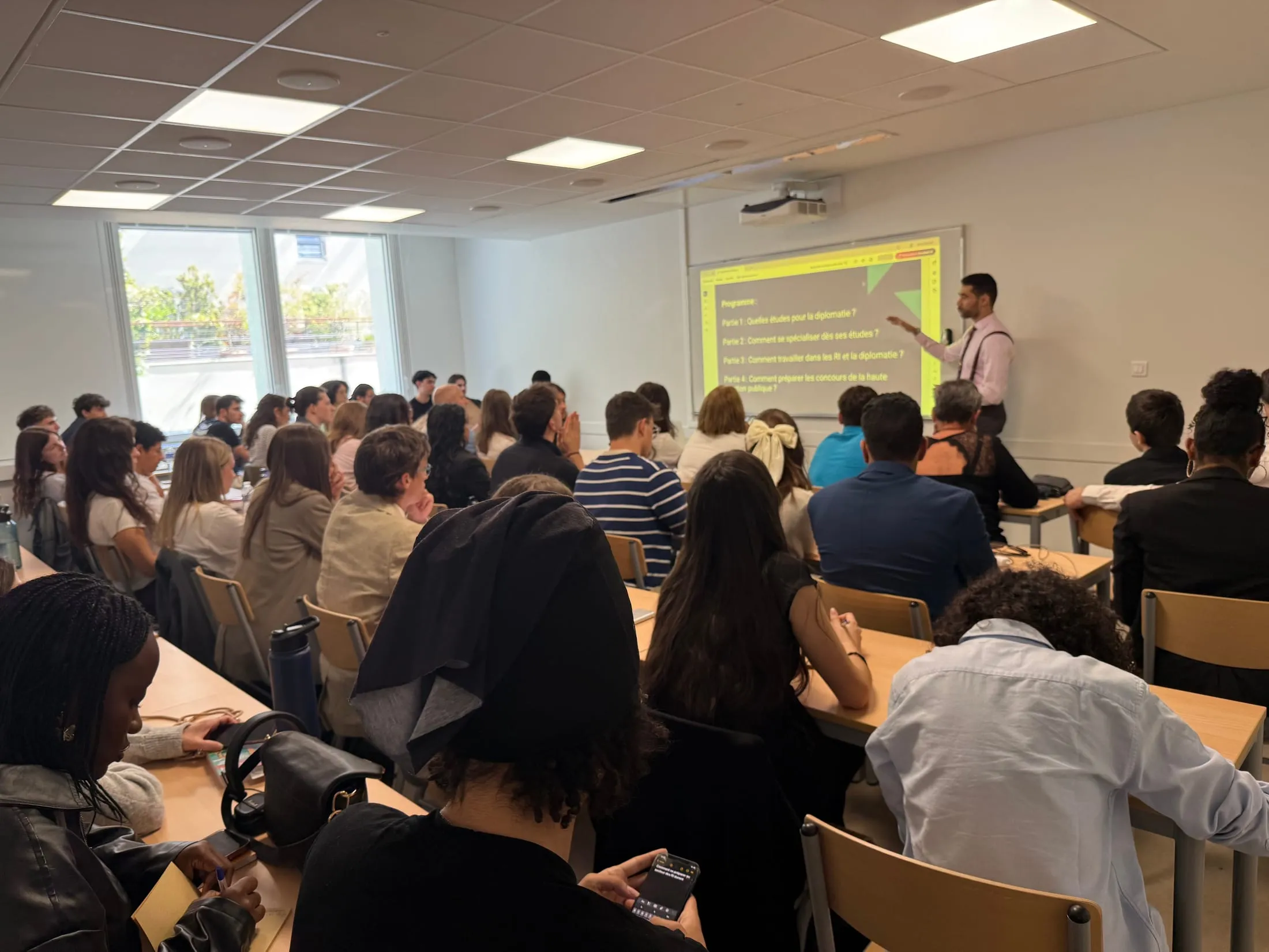 Kevan Gafaïti devant une salle d’étudiants, présentant un programme sur les études en diplomatie